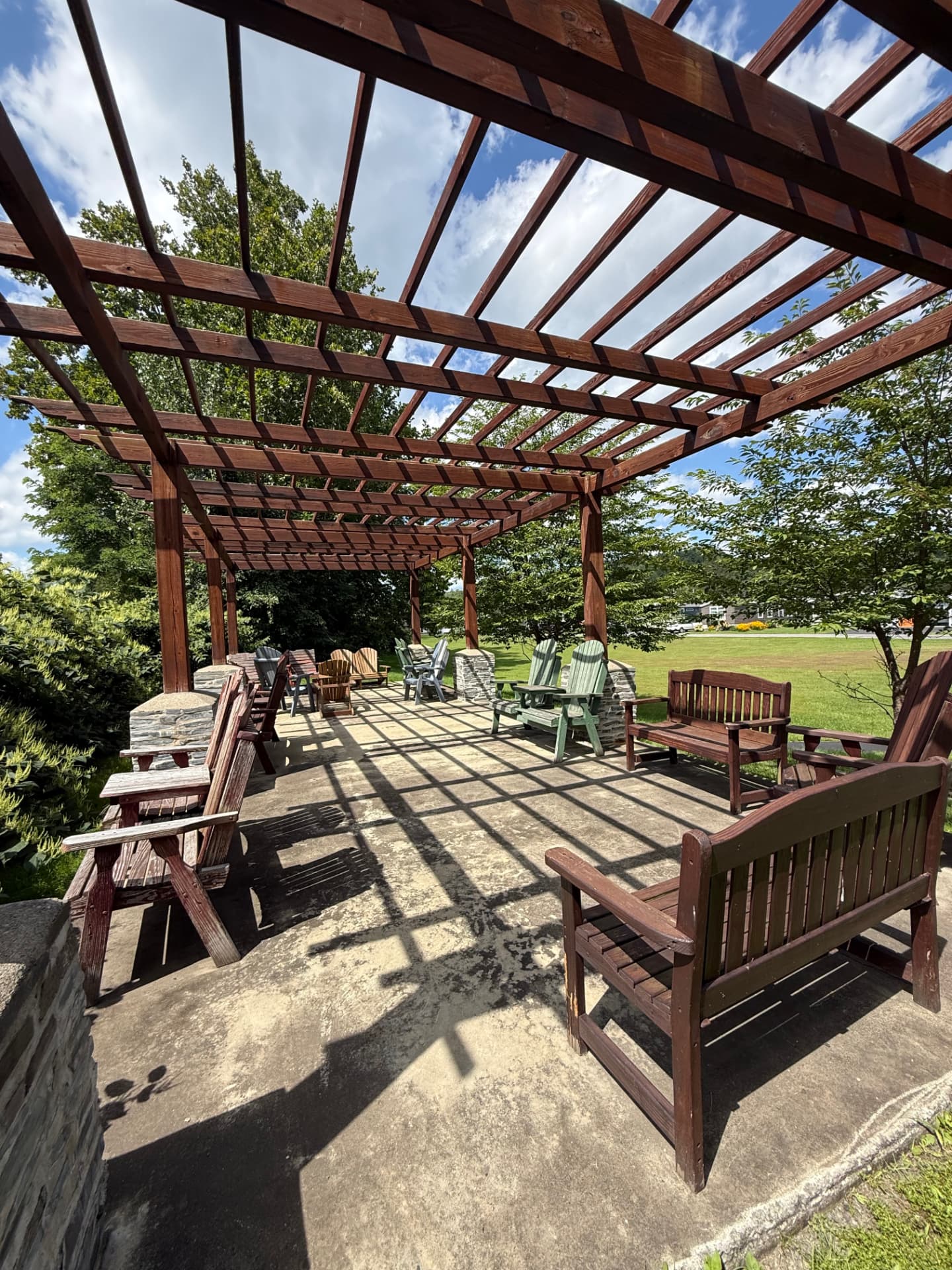 Adirondack chairs and benches gathered under the Tuscany Meadows pergola